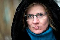 Headshot of a thirty year old white woman wearing a hoody, looking serious, Brussels, Belgium.