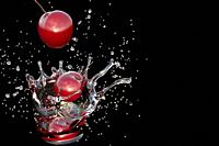 Splash of water with a falling cherry.