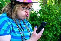 Portrait of a 39 year old white woman with the Down Syndrome, having a video call with her family outdoors, Tienen, Belgium.