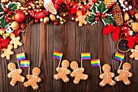 Christmas background of gingerbread cookie men with rainbow flags on wooden table.