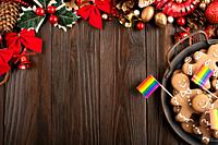 Christmas background of tray with gingerbread cookie men and rainbow flags on wooden table.
