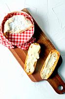 Toasted bread rolls with camembert cheese on a wooden board.