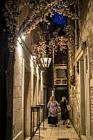 People walking in a narrow alley in the Diocletian's Palace at night, Split, Croatia.