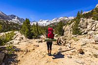 Woman backpacking under Sierra Nevada Mountains in Little Lakes Valley, John Muir Wilderness, California USA.