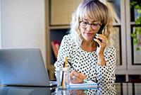Businesswoman busy in a phone call taking notes and work at the office. Young woman work with laptop and mobile device. Business job concept lifestyle...