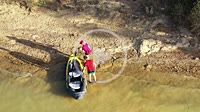 Young couple moving an inflatable canoe in a swamp bank. Drone view. 4K. Alloz reservoir, Navarra, Spain, Europe