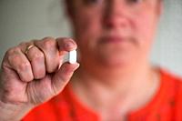 Woman holding a pill.