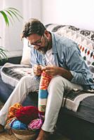 Man doing knit work with needles to relax and enjoy indoor time at home. Hand made work relaxation therapy. People doing hobby or diy leisure activity...