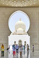 Worshippers and visitors at the entrance of Sheikh Zayed Mosque. Abu Dhabi, United Arab Emirates.