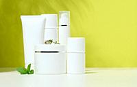 White plastic container tube, a jar with a lid for cosmetics on a green background with a shadow from a palm leaf. Advertising and promotion.