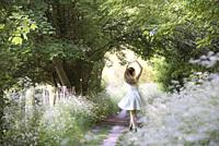 Girl performing a position (5th) of classical dance on a small country trail bordered by umbellifers on the edge of the forest, Eure-et-Loir departmen...