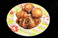 Plate with chocolate croissants and muffins for breakfast.