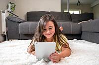 Adorable little girl using a digital tablet on the floor at home. High quality photography.