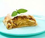 Slice of apple strudel on a round plate, white background.