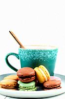 Colored macaroons on blue plate with white background.