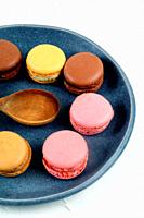 Colored macaroons on blue plate with white background.