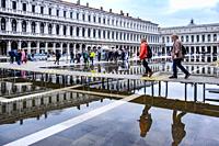 Visible effect of climate change on Venice; people using a boardwalk to avoid getting wet feet in Venice, Italy, Europe.