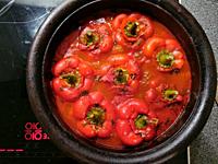 Stuffed peppers in tomato sauce are cooked in an iron pot on the stove.
