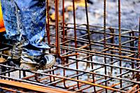 High-contrast image of a construction worker preparing a structure for pouring concrete rebar.