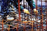 High-contrast image of a construction worker manipulating a rebar structure.