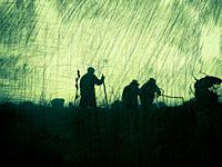 Three men hiking on a mountaintop on a dark, stormy day.