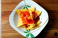 Plate with nachos and hot sauce.