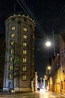 Copenhagen, Denmark Pedestrians walking at night in the historic old town near the landmark Round Tower.