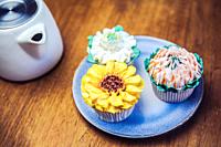 Various cupcakes decorated with colorful flower icing on wooden table, floral bouquet, wedding cake, High tea, Holiday concept Mothers day.