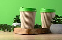 Paper brown cups with a plastic green lid for coffee and tea on a green background.