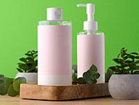 Two bottles for cosmetics with a pink paper label on a green background. Bottle for tonic, gel.