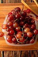 Cluster of red grapes close up on wooden board.