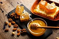 Honeycomb on slate tray with honey and nuts on kitchen table.