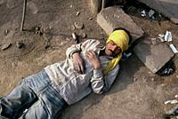 A poor man is sleeping on the ground in the street ( Delhi, India).