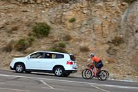 Two riders training with a support car in the mountain pass of La Morcuera in the Community of Madrid.