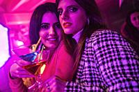 Couple of sensual and cute friends girl in nightclub with alcoholic drink.