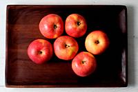 Red apples on wooden tray.