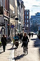 Copenhagen, Denmark A woman biking on the landmark Studiestræde street in the downtown in the springtime sunshine.