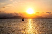 Sunset at Aegean sea at Evia island in Greece. Sun setting behind the Pelion mountain.
