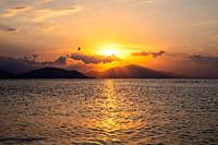 Sunset at Aegean sea at Evia island in Greece. Sun setting behind the Pelion mountain.
