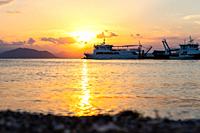 Ships and boats in the harbour at sunset at the island of Evia in Greece in town called Pefki.