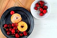 Dish with delicious doughnuts and cherries.