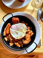 Migas with fried egg, bacon and chorizo. Spain.