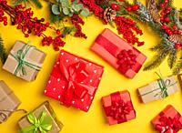 Christmas decor, gifts wrapped in red paper on a yellow background, top view.