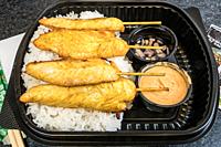 A take-out plastic container with Satay chicken.
