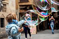 Gothic Quarter Joy: A child's delight as they play with oversized soap bubbles, bringing winter wonder to the historic streets of Barcelona.