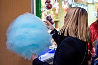 In the holiday spirit: A woman joyfully indulges in a vibrant blue cotton candy at Barcelona's Christmas Fair, adding a touch of sweet magic to the fe...