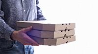 Caucasian male hands hold three pizza boxes side view with copy-space.