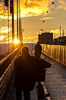 Stockholm, Sweden Bicyclists on the Lljeholmen Bridge during winter mid-afternnon sunset.