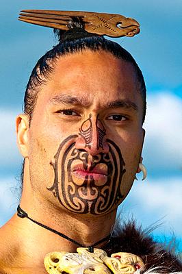 A Maori warrior with a ta moko facial tattoo performs a war haka dance