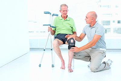 Doctor examining his patient knee-stock-photo